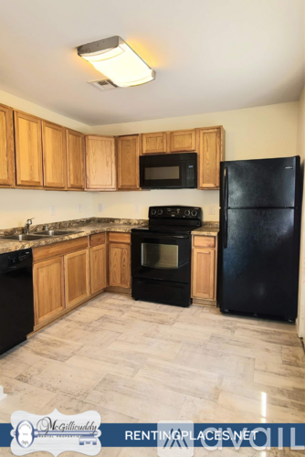 A kitchen with wooden cabinets and black appliances.