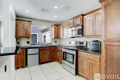 A kitchen with wooden cabinets and black countertops.