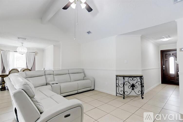 A white living room with a long couch and a table with a wrought iron base.