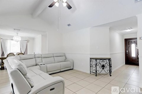 A white living room with a long couch and a table with a wrought iron base.
