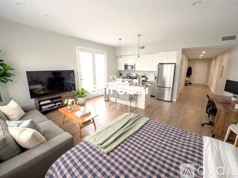 A bedroom with a bed, couch, and television in a modern apartment.