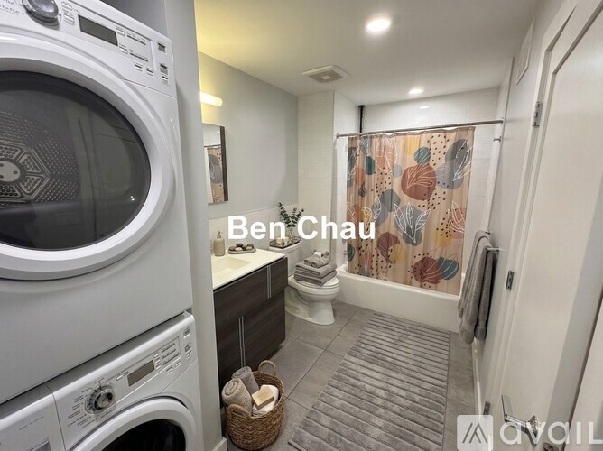 A washing machine is in the foreground of a laundry room.