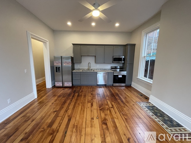 A kitchen with wooden floors and a ceiling fan.