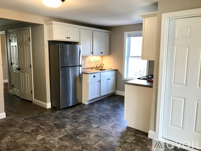 A kitchen with a refrigerator, cabinets, and a counter.