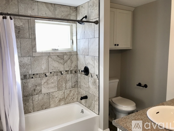 A bathroom with a marble tile shower and a white bathtub.