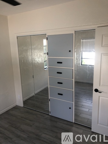A room with a white door and a cabinet with drawers.