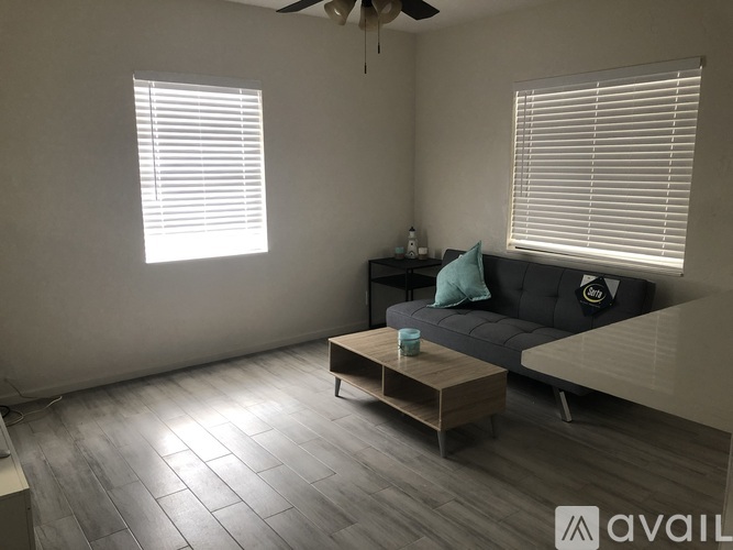 A living room with a grey couch, a wooden coffee table, and a ceiling fan.