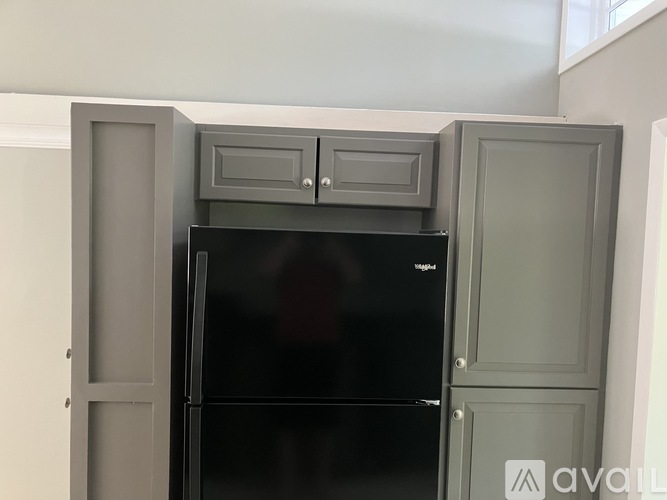 A black refrigerator with a grey cabinet above it.