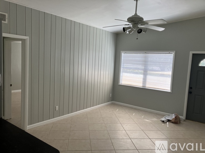 A room with a ceiling fan and a window with blinds.