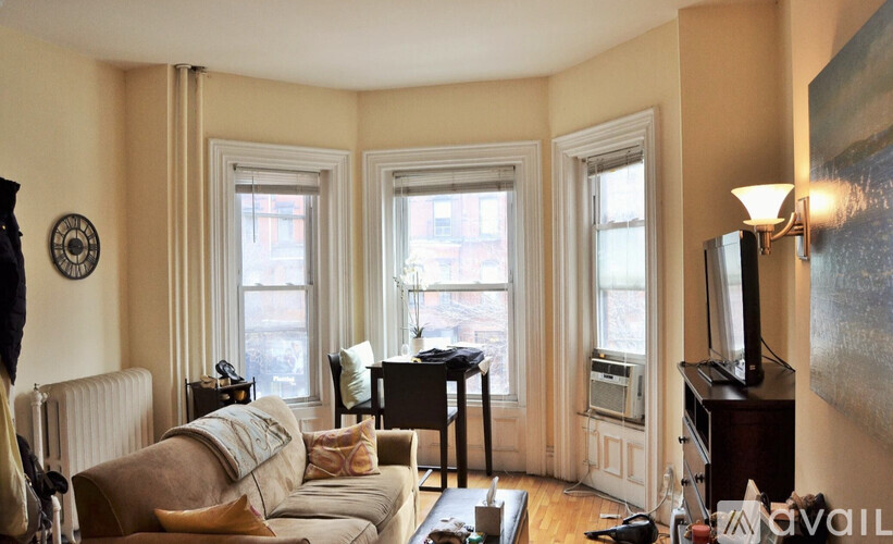 A living room with a couch, a chair, a piano, and a television.