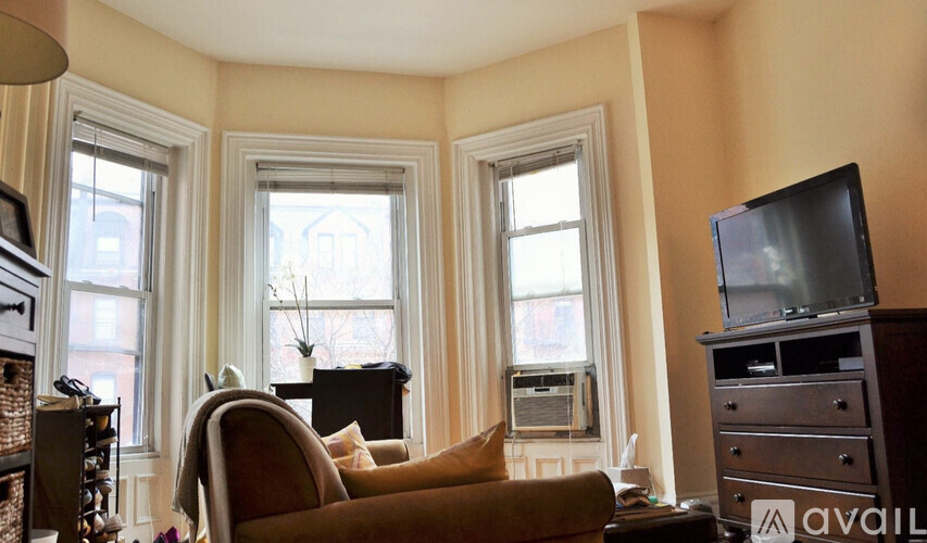 A living room with a brown couch, a television, and a fireplace.