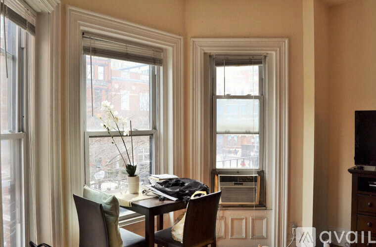 A table with chairs and a vase of flowers sits in front of a window.