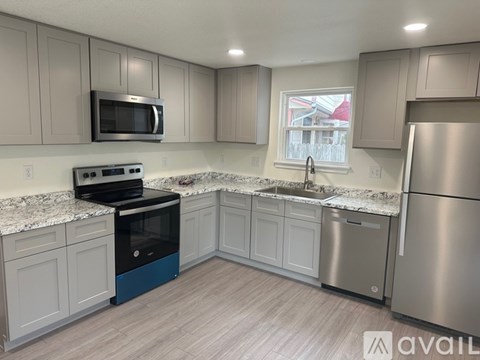 A kitchen with a stainless steel refrigerator, microwave, and oven.