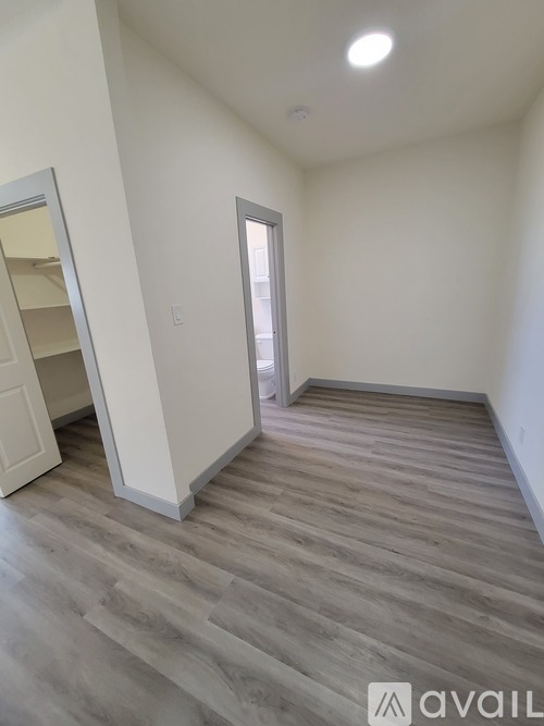 A room with wooden flooring and a doorway leading to another room.