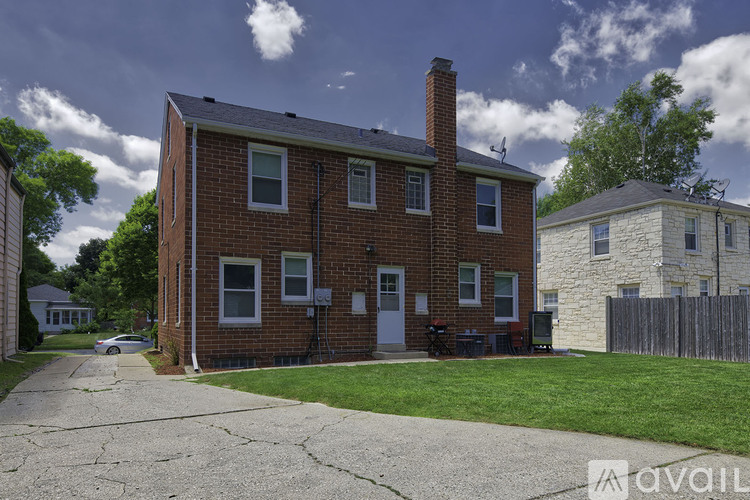 A brick house with a chimney and a driveway in front.