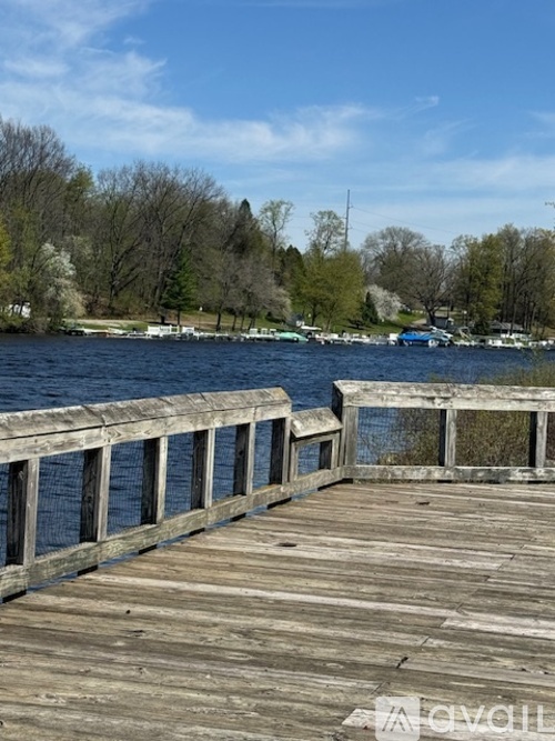 A wooden dock extends into a lake with trees in the background.