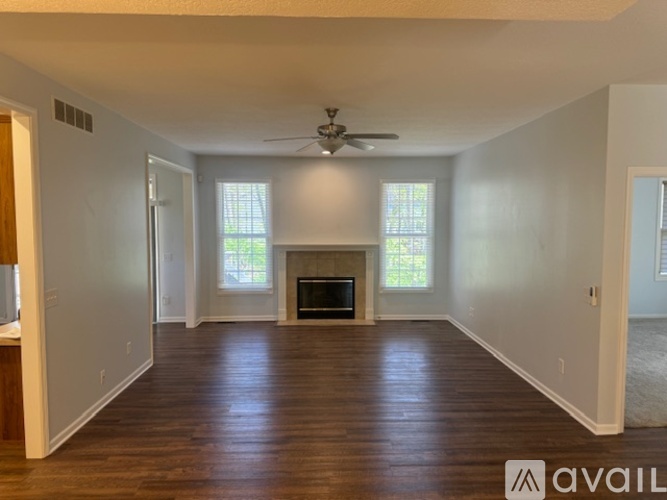 A spacious living room with a fireplace and a ceiling fan.