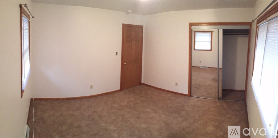 A room with a carpeted floor and a brown door.