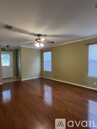 A room with a ceiling fan and wooden flooring.