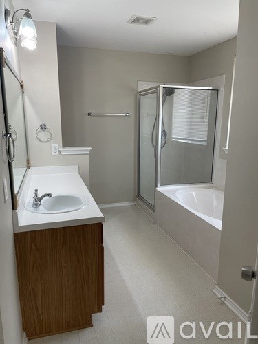 A bathroom with a sink, mirror, and bathtub.