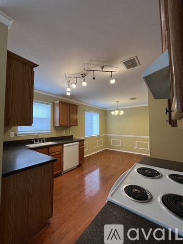 A kitchen with a stove top oven and wooden cabinets.