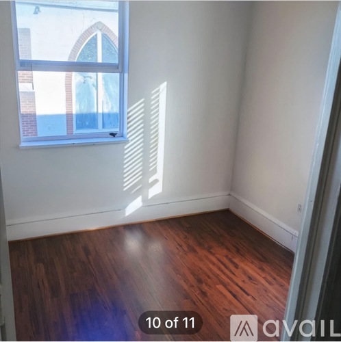 A room with wooden floors and a window letting in sunlight.