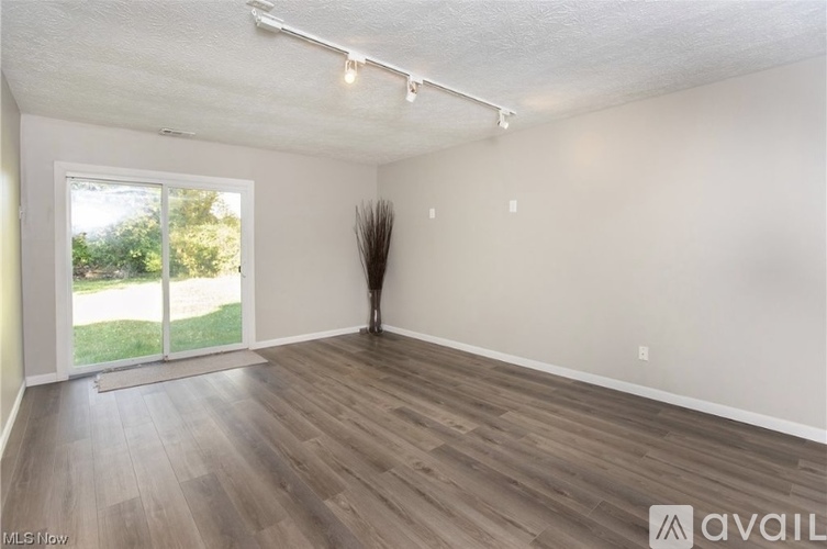 A room with wooden flooring and a large window overlooking a green area.