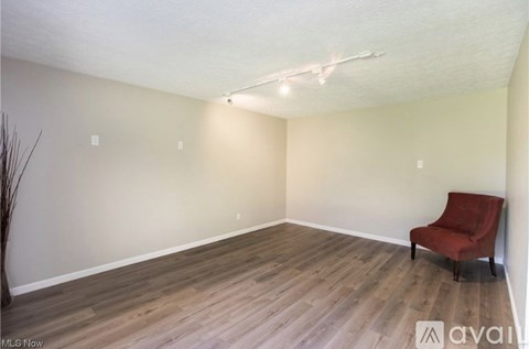 A room with a red chair and wooden flooring.