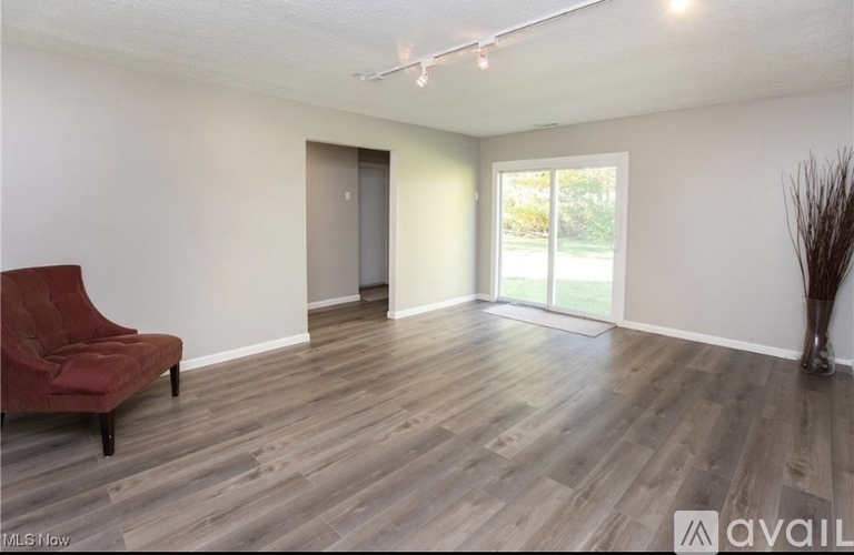 A room with a red chair and wooden flooring.