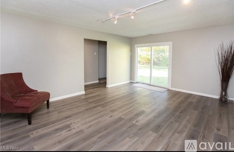 A room with a red chair and wooden flooring.