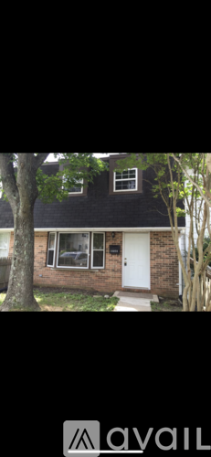 A house with a white door and a tree in front.