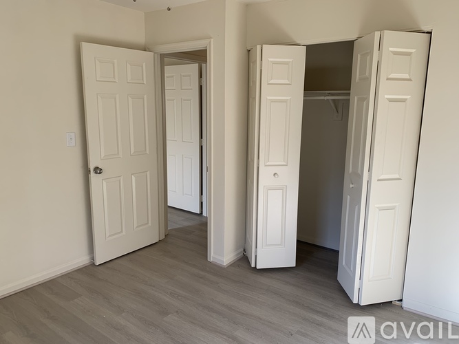 Three white doors in a room with wooden floors.