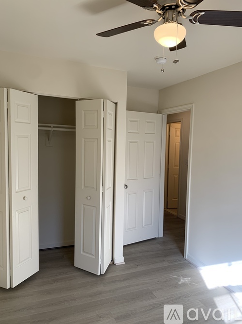A room with a ceiling fan and three doors.