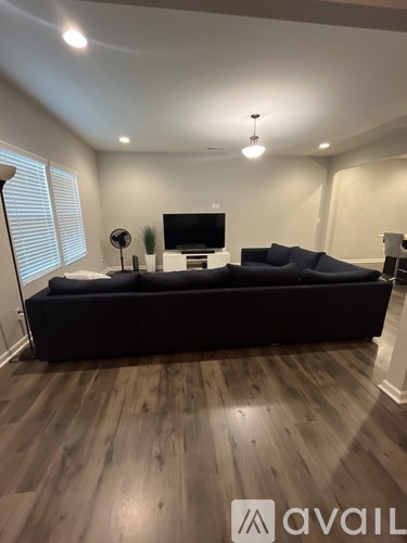 A living room with a black sofa and wooden flooring.