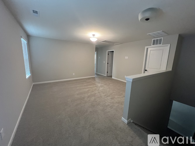A spacious room with a carpeted floor and a window on the left side.