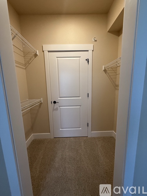 A white door is in the middle of a hallway with a carpeted floor.