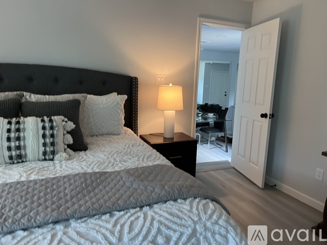 A bedroom with a large bed and a lamp on a nightstand.