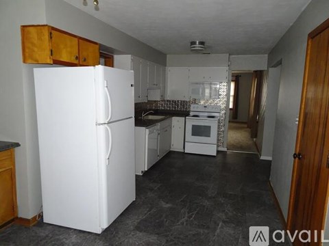 A kitchen with a white refrigerator and wooden cabinets.