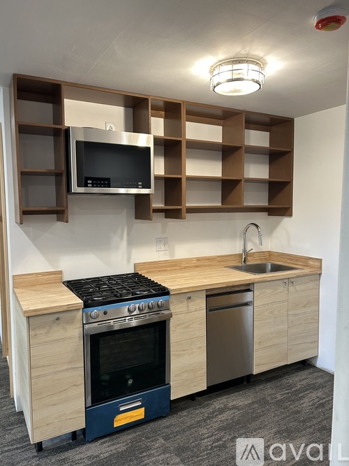 A kitchen with a stove, sink, and shelves above the counter.