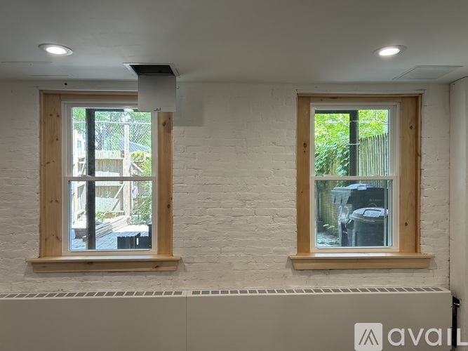 Two windows with wooden frames on a white brick wall.