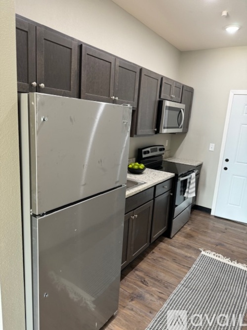 A kitchen with a refrigerator, microwave, oven, and cabinets.