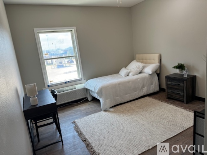A bedroom with a bed, nightstand, and window.