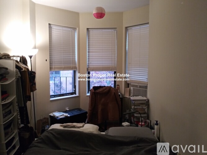 A bedroom with a bed, nightstand, and window with blinds.
