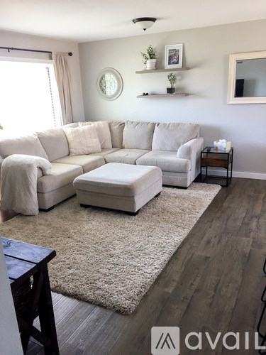 A living room with a large sectional sofa and a small ottoman.