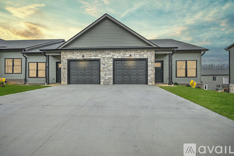 A house with a stone facade and two garage doors is available for sale.