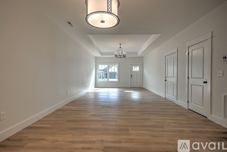 A long hallway with wooden floors and a chandelier hanging from the ceiling.