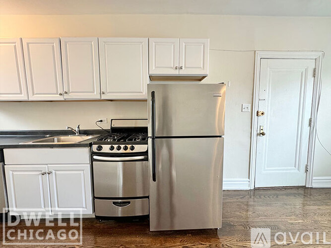 A kitchen with white cabinets and a stainless steel refrigerator.