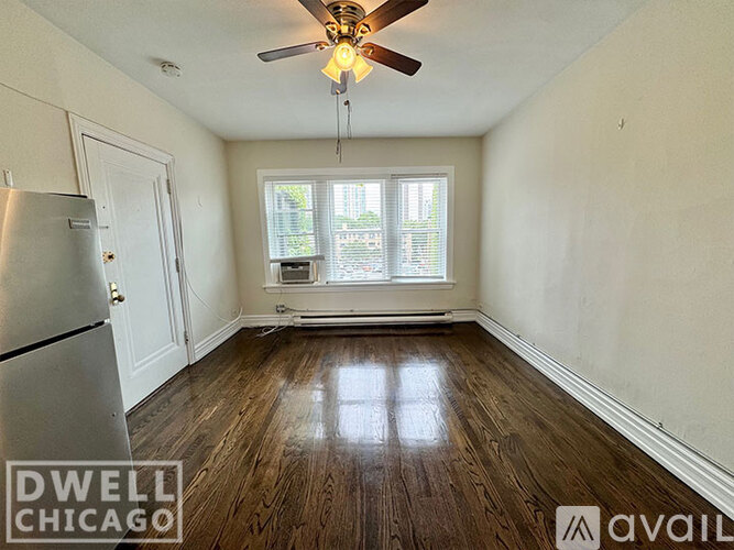 A room with a ceiling fan and a window with a view of a building outside.