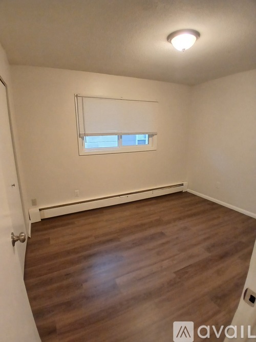 A room with wooden flooring and a window with blinds.