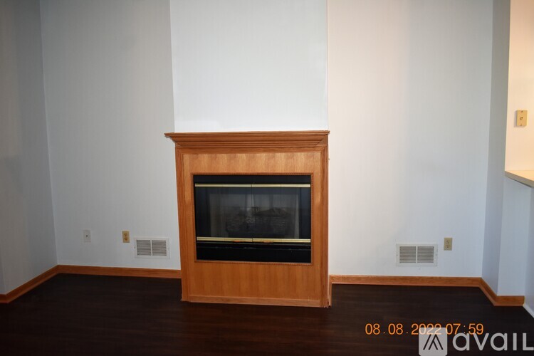 A wooden fireplace in a room with white walls.